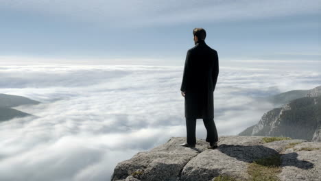 man overlooking a vast sea of clouds from a mountain cliff