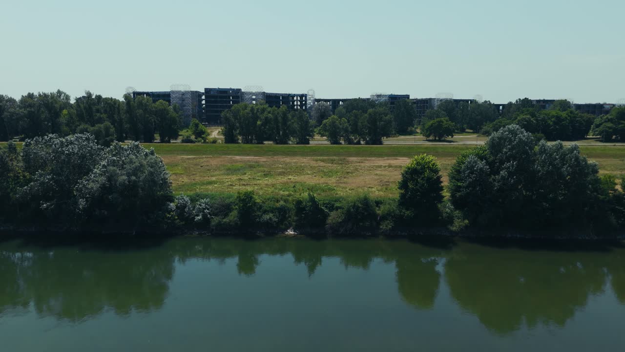 drone shot of unfinished hospital buildings hidden behind trees near Sava embankment in Zagreb