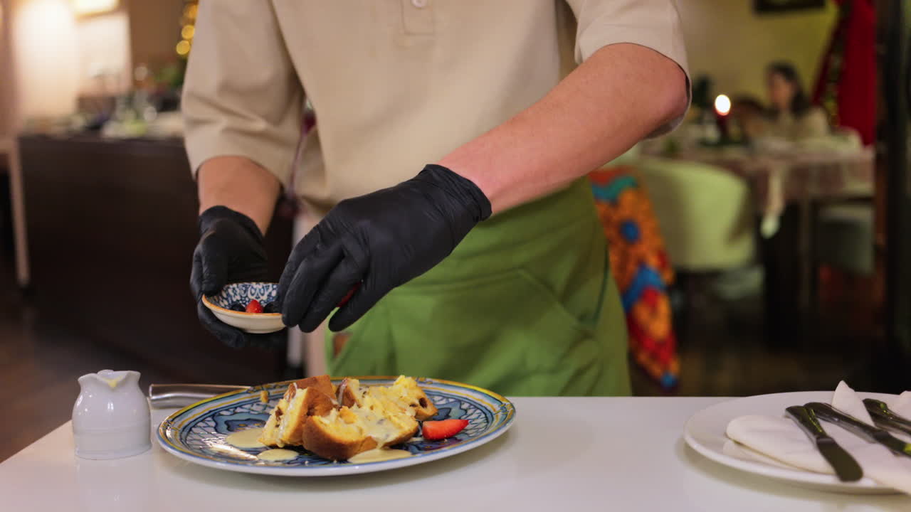 Waiter pouring condensed milk and adding berries on multiple pieces of panettone at restaurant
