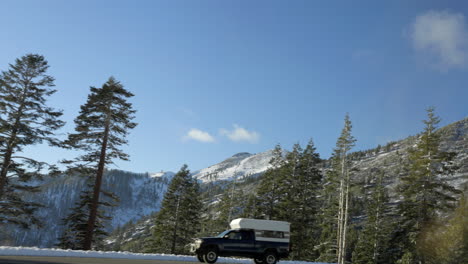 view out car window in lake tahoe as mountains and douglas firs pass by with a camper parked on the side of the road