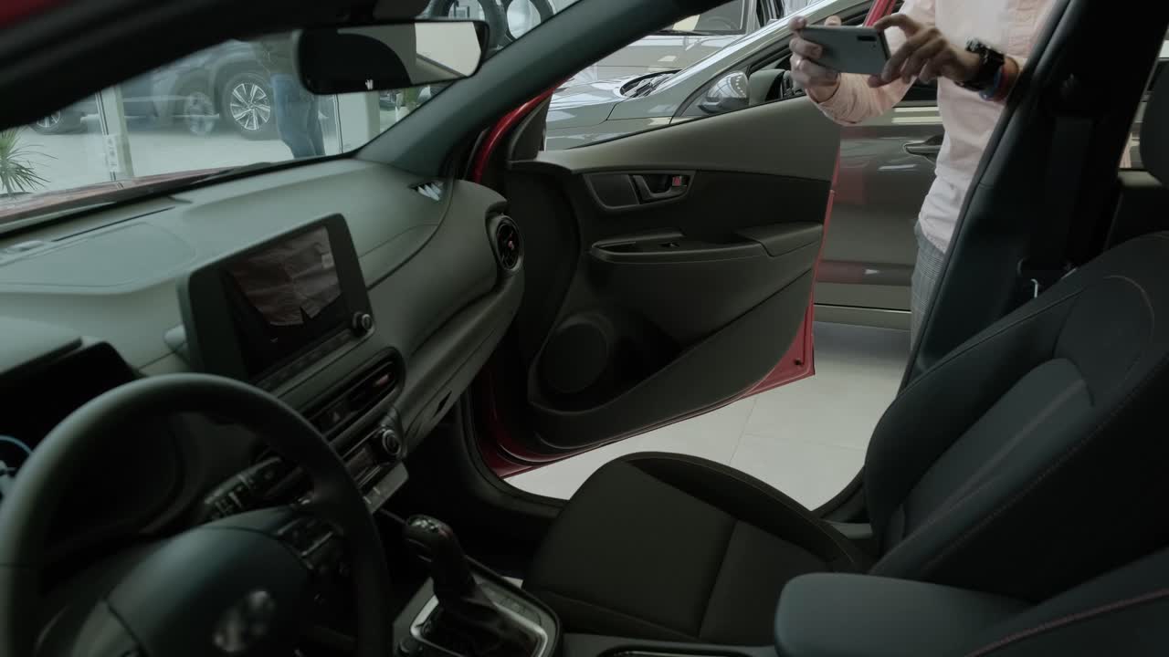 새로운 자동차의 검은색 인테리어 클로즈업: 자동차 쇼에서 새로운 자동차가 판매됩니다. 러리 매니저는 판매하는 새로운 자동차의 사진을 찍습니다.