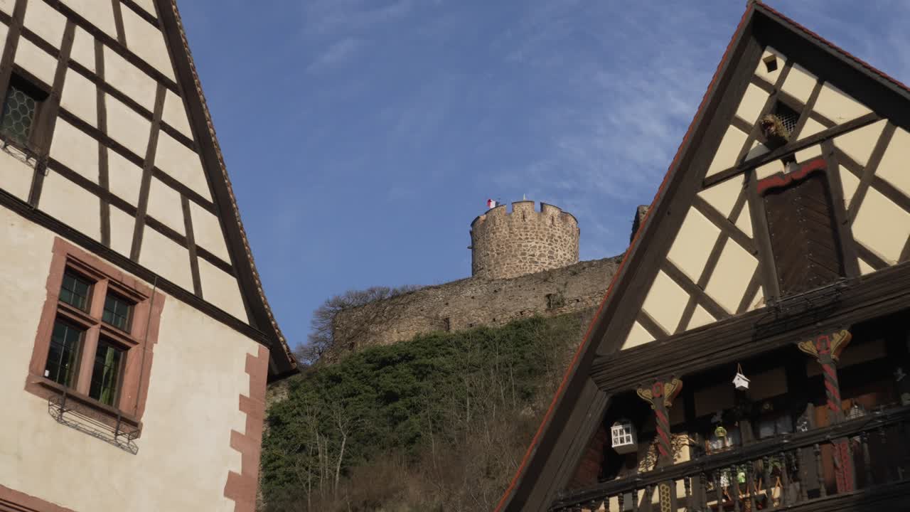 Charming half timbered houses with castle tower in the background on a clear blue sky