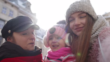 Mujeres-Turistas-Tomando-Fotos-Selfie-En-Un-Teléfono-Móvil-Con-Una-Niña-Adoptiva-En-Las-Calles-De-La-Ciudad-De-Invierno