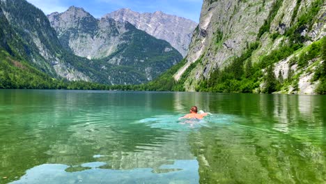 Mann-Taucht-In-Kristallklares-Wasser-Eines-Idyllischen-Sees,-Umgeben-Von-Bergen,-Zeitlupenaufnahme---Alpenberge-Im-Sommer-Und-Lebendige-Farben