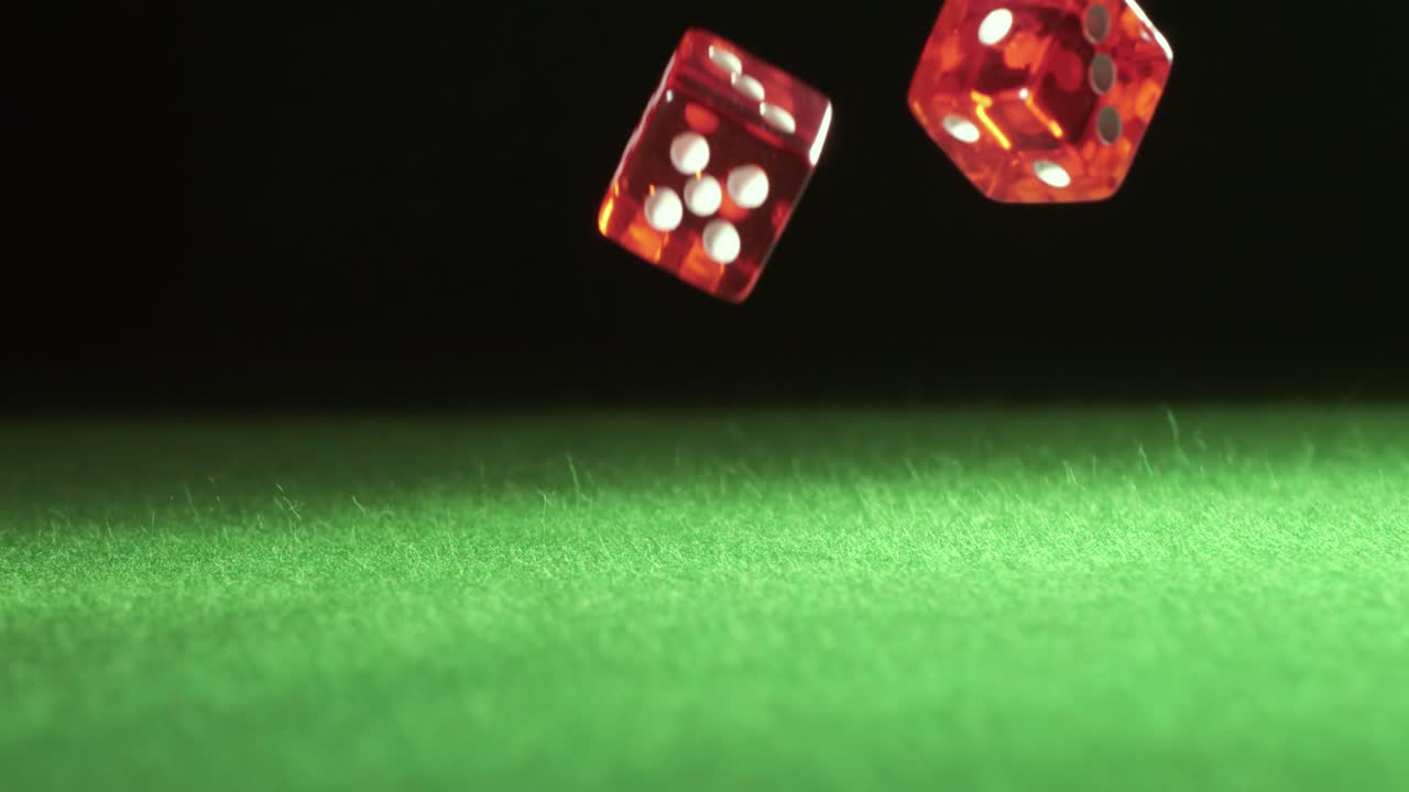 los dados rojos caen y rebotan en la mesa verde sobre un fondo oscuro. filmado con una cámara súper lenta de 1000 fps.