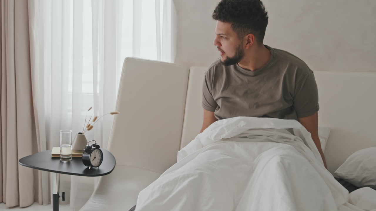 Giovane uomo latino che si sveglia a letto a casa