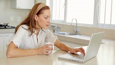 hermosa morena bebiendo café y usando una computadora portátil