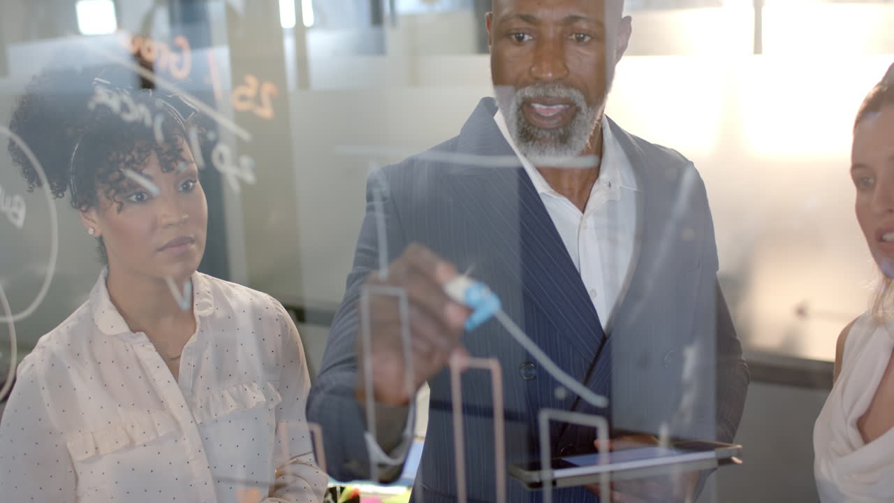 African american businessman writing on glass wall in office with copy space