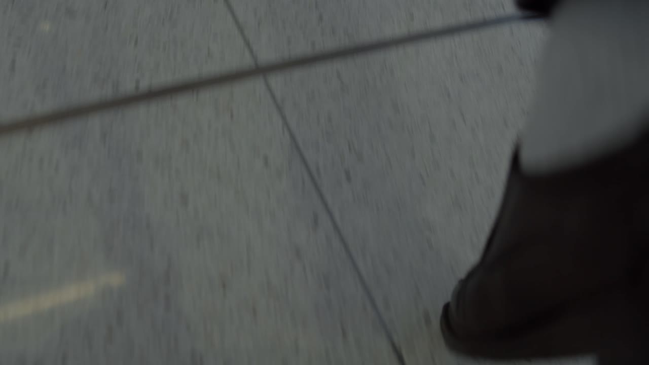 Slow motion of a man's feet wearing loafers and taking a step in an airport terminal tiled floor - medium close up