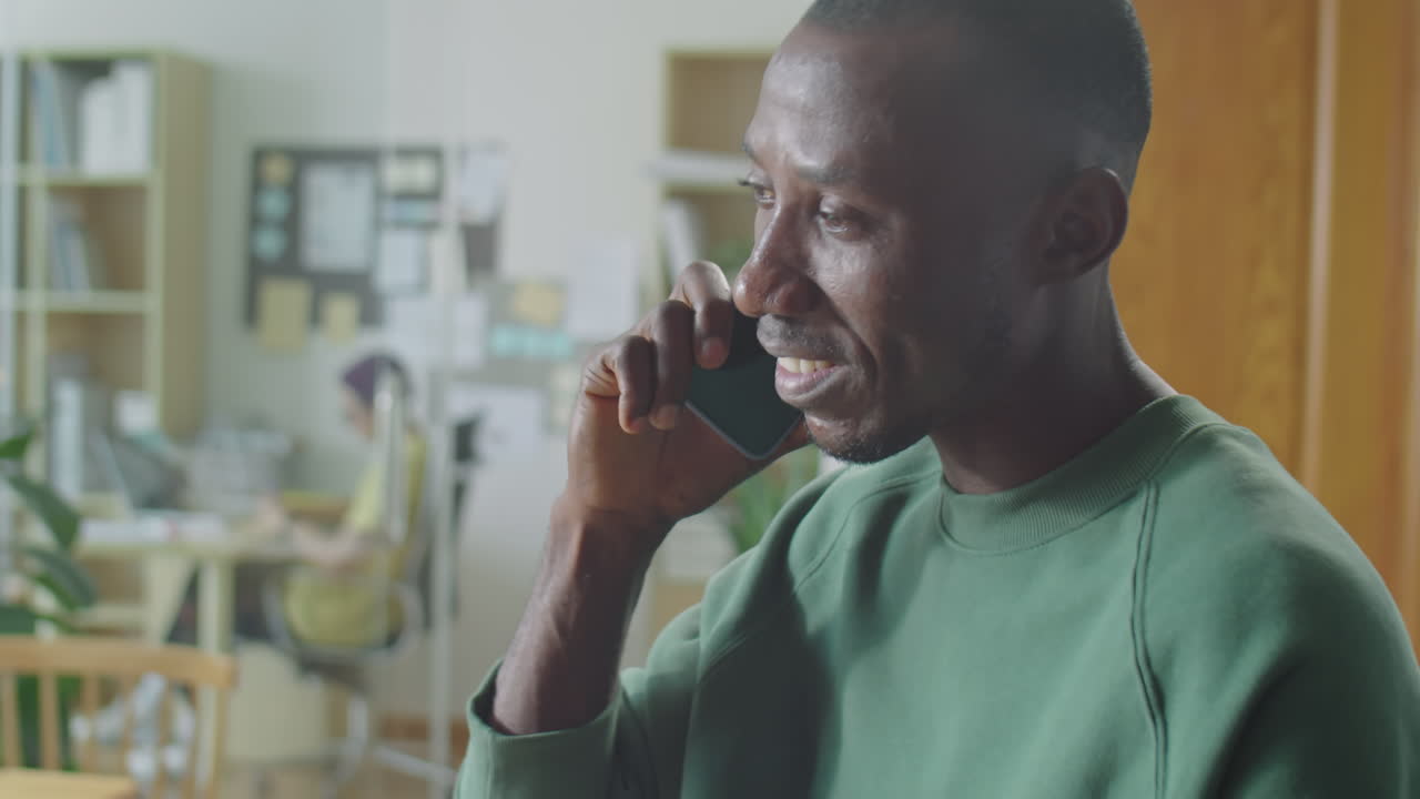 Black Man Holding Coffee and Speaking on Phone in Office