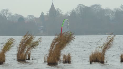 person kite surfing on local lake water on windy day with majestic castle in background