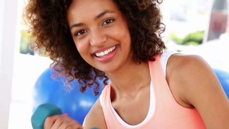 Mujer-En-Forma-Levantando-Pesas-Y-Sonriendo-A-La-Cámara