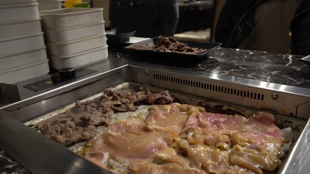 puedes ver trozos de carne y pollo en una parrilla coreana.