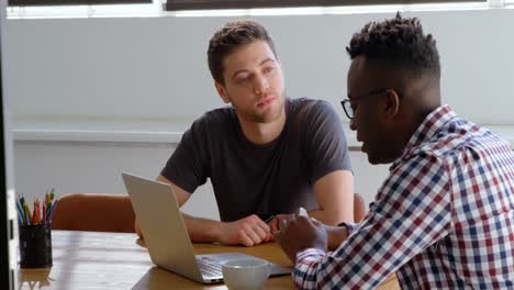 Front-view-of-young-mixed-race-business-team-planning-and-sitting-in-conference-room-of-modern-offic