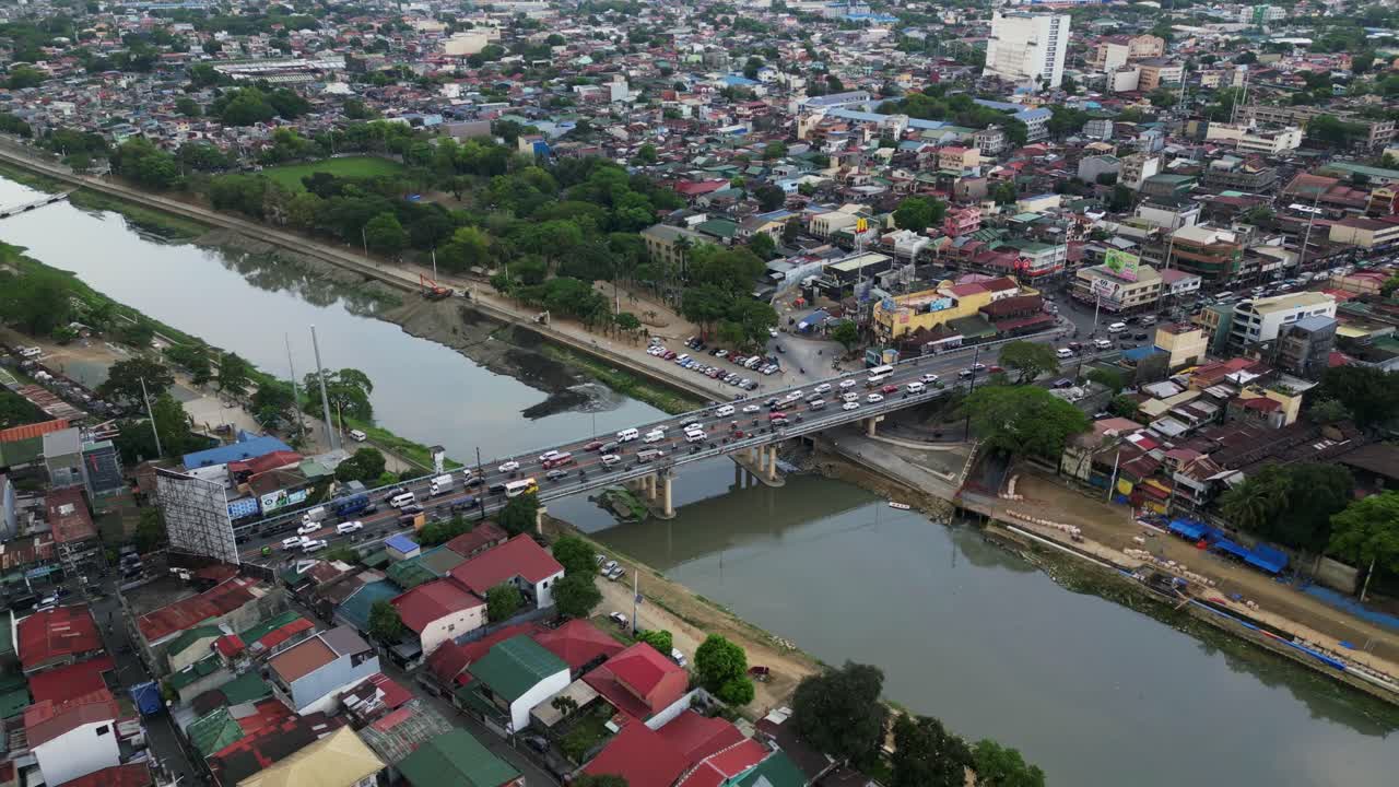 Aerial pullback of dense traffic at Marikina City bridge crossing Marikina River during daytime.