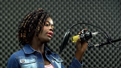 african american alfro hair black woman sing a song loudly and express feeling with power sound over hanging microphone condenser