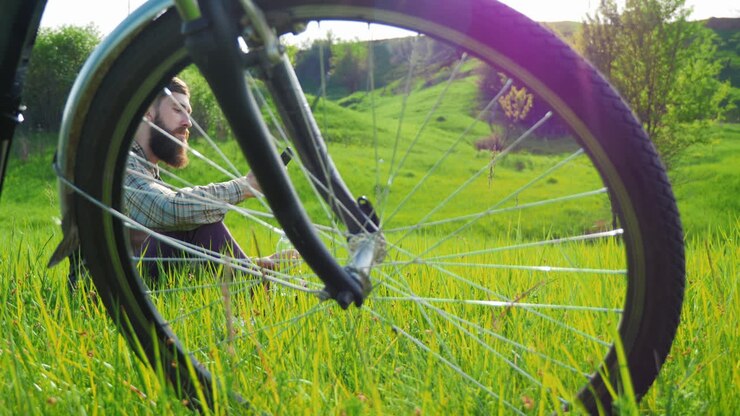 ein junger hipster-mann ruht auf einer wiese in der nähe eines fahrrads