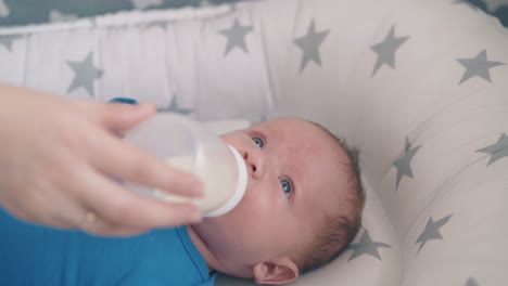 Mama-Gibt-Dem-Weinenden-Baby-In-Einem-Weichen-Kokon-Eine-Flasche-Milch
