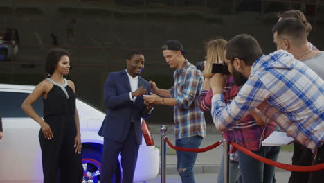 celebrities on red carpet interacting with paparazzi and fans