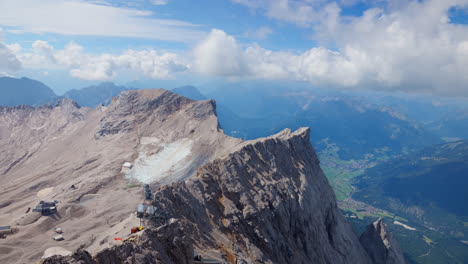 Curved-jagged-rough-ridge-line-of-mountain-in-Zugspitze,-Germany,-cloudy-blue-sky