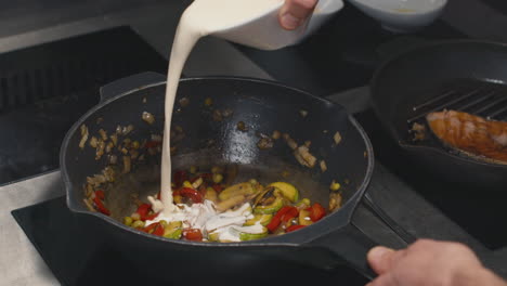 adding cream to pan-fried vegetables