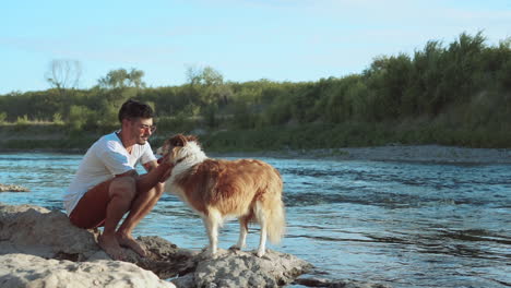 hombre y su perro en la orilla del río