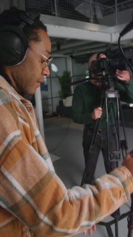 video vertical de un grabador de sonido masculino y un operador de cámara trabajando en un set de filmación filmando una película o video en el estudio 6