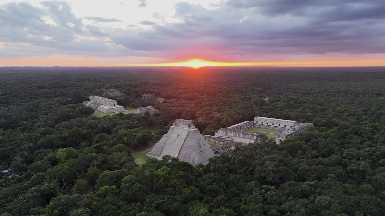 Aerial sunset drone approach to Mayan city of Uxmal in Yucatan, Mexico, surrounded by dense jungle