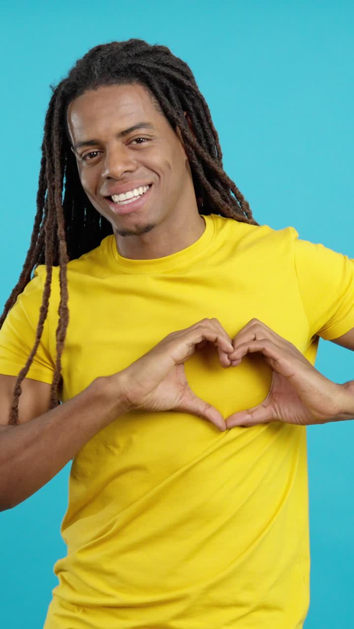 Uomo con i dreadlock che forma un cuore con le mani