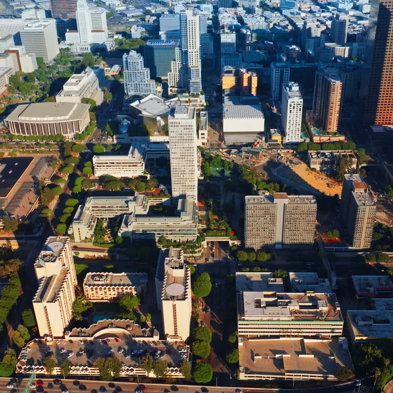Rising above sunlit Los Angeles downtown. Crazy traffic on the roads of metropolis from aerial view