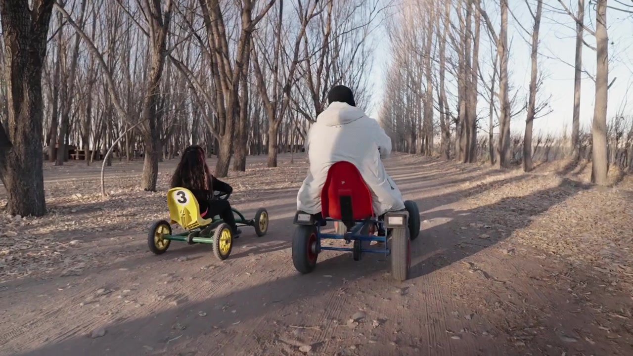 Aktiv far og datter har det sjovt med at køre pedalkarts gennem et rekreativt område