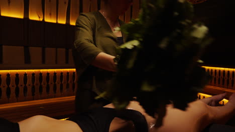 Woman Receiving Sauna Treatment with Herbal Broom