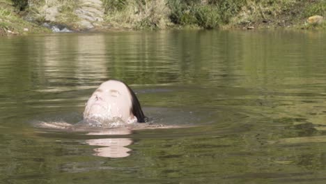 close up shot of girl going underwater in a dam