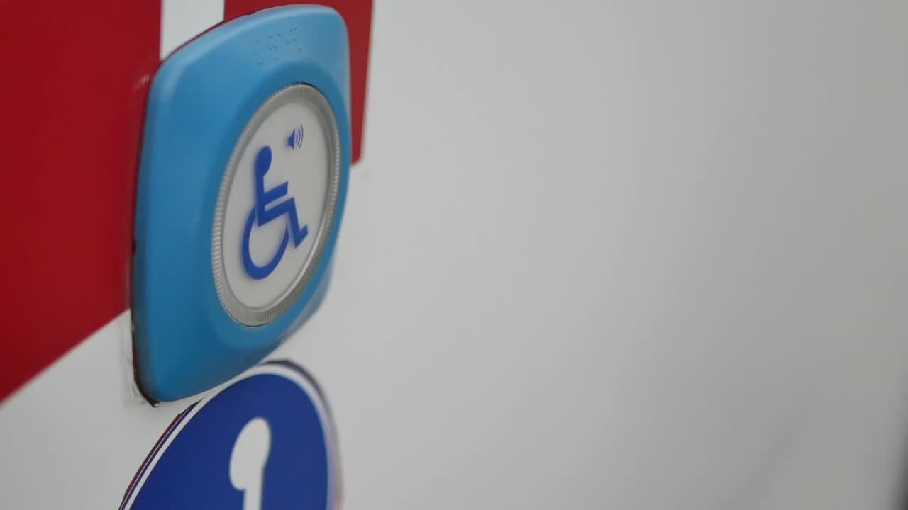 A hand pressing an accessibility button with a wheelchair symbol