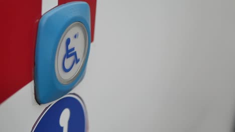 a hand pressing an accessibility button with a wheelchair symbol