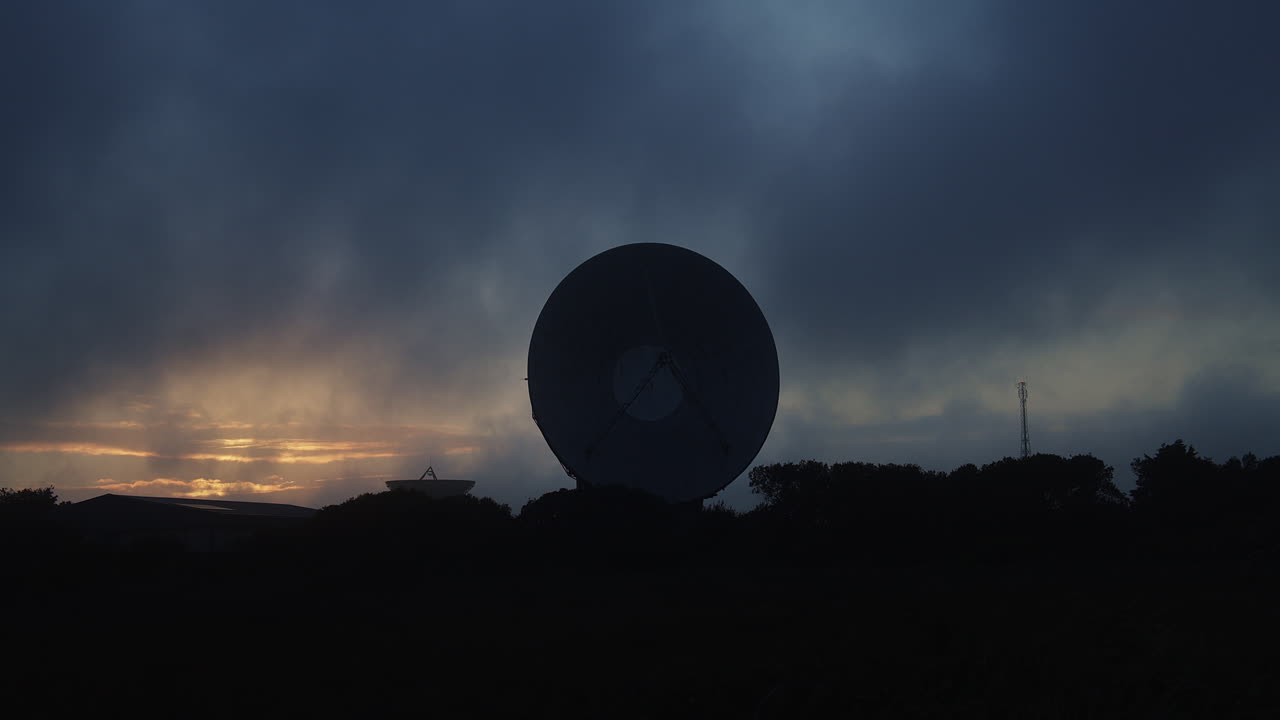 lapso de tiempo de nubes moviéndose sobre un plato de radiotelescopio, noche oscura y sombría