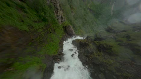 Fpv-flug-Den-Bjødnabykset-wasserfall-Zwischen-Begrünten-Bergen-An-Einem-Regnerischen-Tag-In-Norwegen-Hinunter