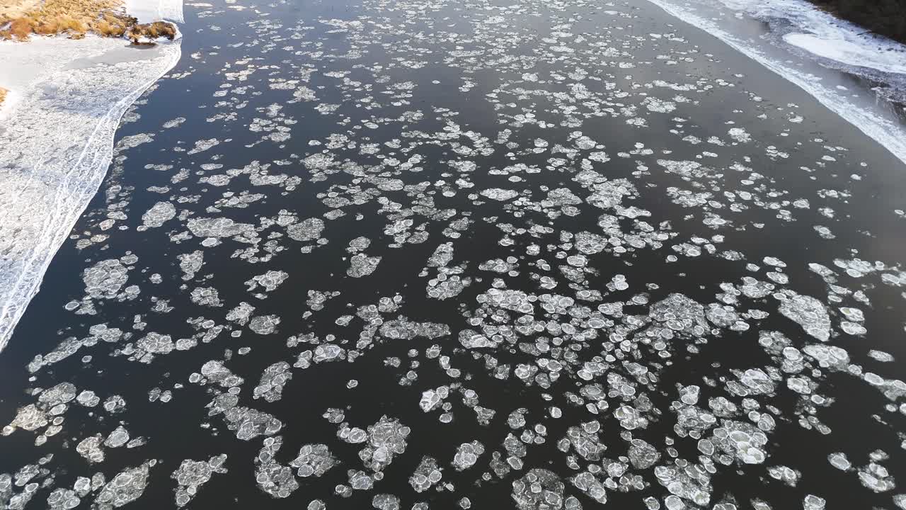 Ice parts flowing in deep blue river, aerial view