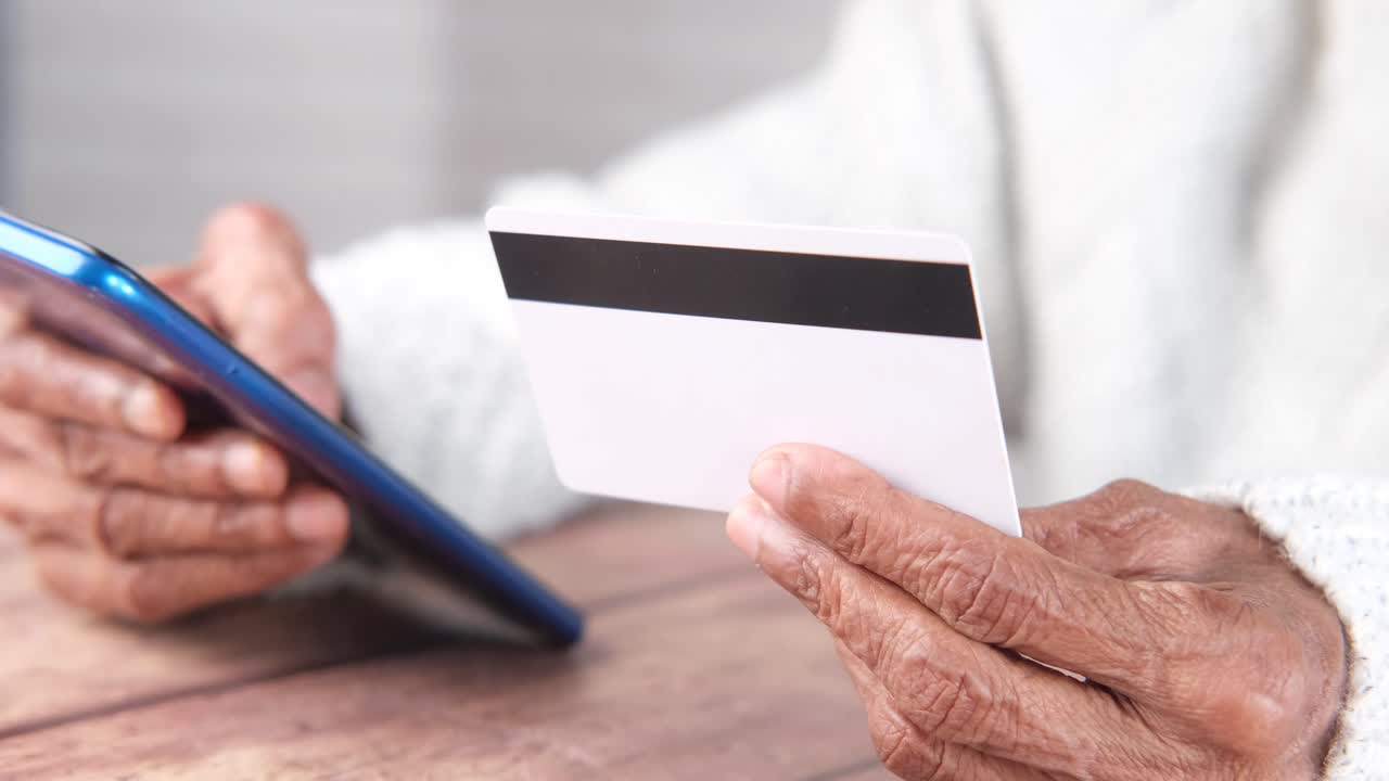 persona mayor que realiza un pago en línea con una tarjeta de crédito