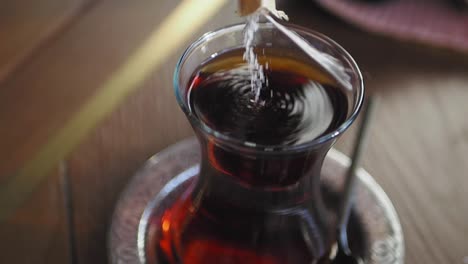 pouring sugar into a glass of turkish tea