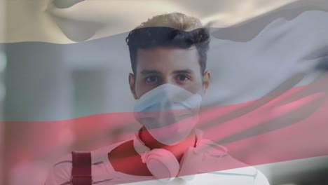 animation of flag of russia waving over man wearing face mask during covid 19 pandemic