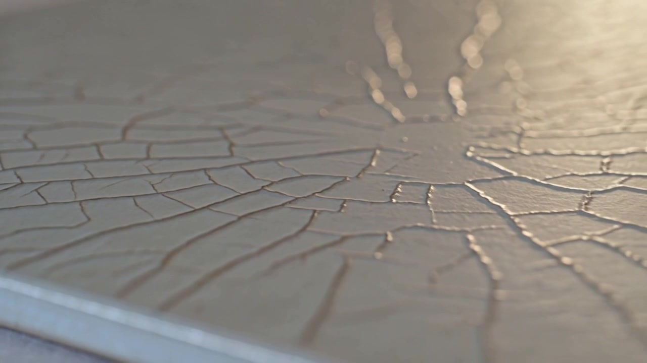 Spostamento della telecamera e cambio di luce che rivelano un pannello dipinto con crepe su un tavolo.