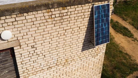 único panel solar en la pared de un viejo edificio de ladrillo blanco