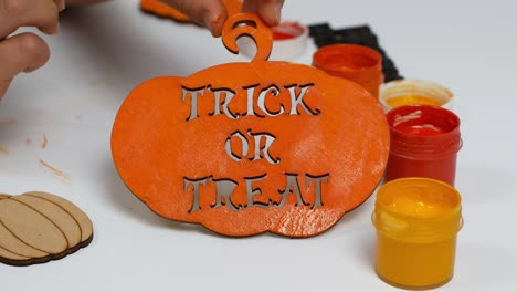 children make their own halloween decor. children paint a pumpkin orange with the inscription trick or treat