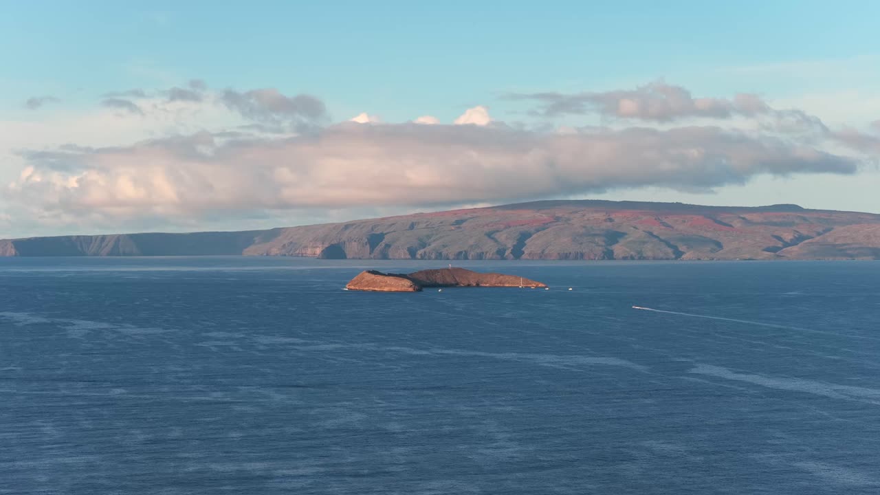 Smooth drone descent to Molokini Crater, revealing the deep blue Pacific and distant coastline. A cinematic travel shot ideal for tourism, documentaries, coastal storytelling, and scenic transitions