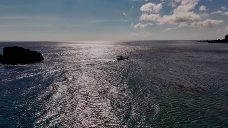 drone shot of cruising boat on ocean during sunny day with surface reflection at orchid island