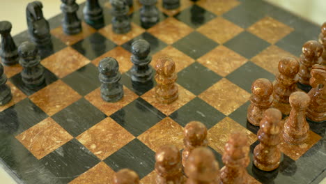 A-brown-and-black-stone-chess-set-in-the-early-stage-of-the-match-with-pawns-being-moved-into-the-center-as-a-strategy-to-win