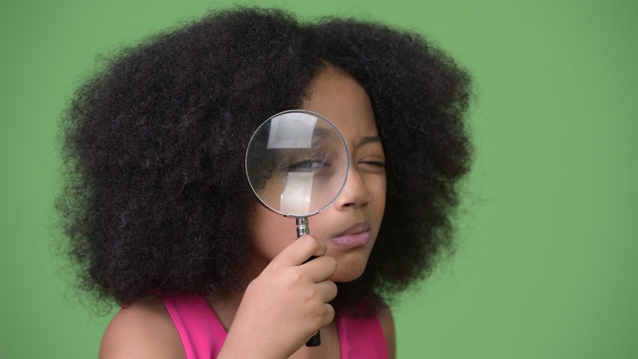 una joven africana con cabello afro usando una lupa