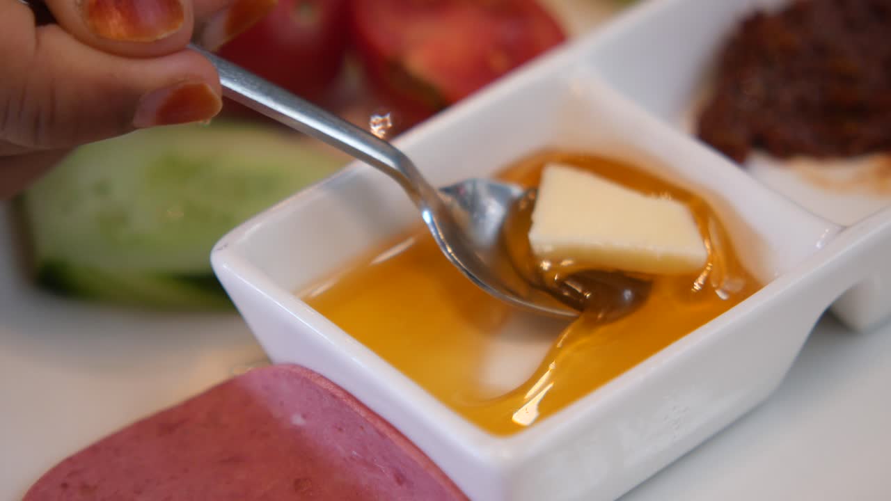 un primer plano de una cuchara sumergiéndose en un plato de miel y mantequilla