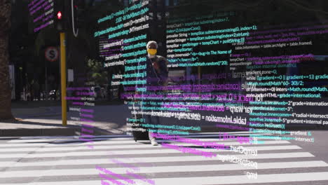 Animation-of-computer-language,-african-american-man-wearing-mask-with-trolley-bag-crossing-street